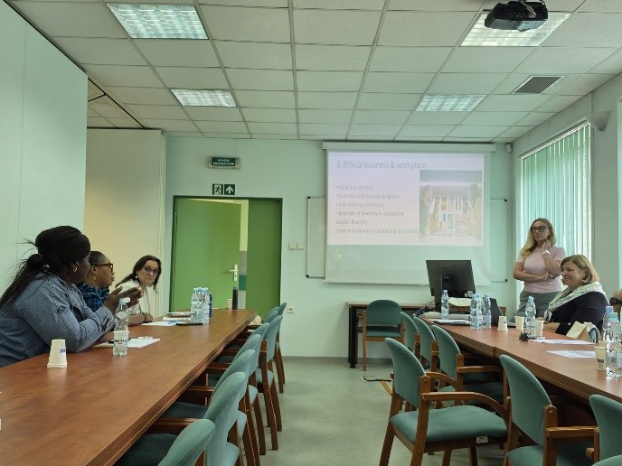 A meeting room with a presentation on ethical business practices. Attendees are seated at a long table, engaged in discussion.