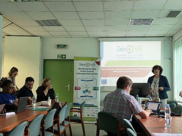 A meeting in a conference room with participants engaged in discussion. A presentation on "Data4Food" is displayed on a screen.